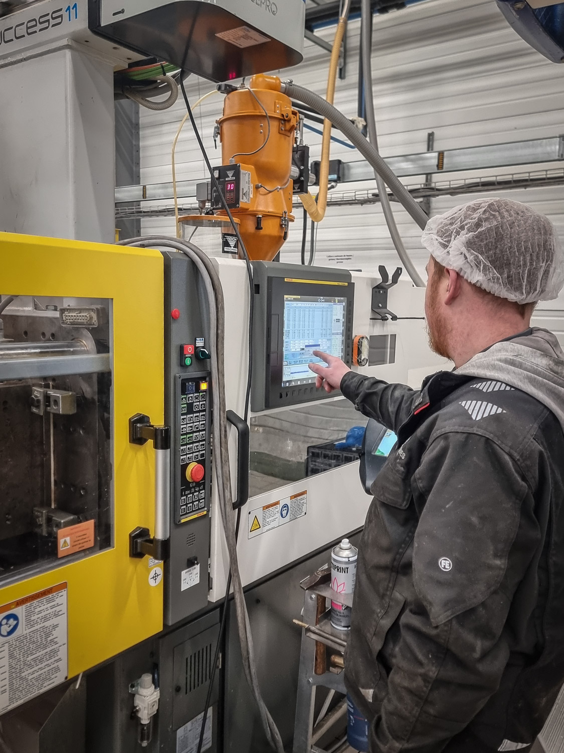 Monteur-régleur vérifiant les paramètres d’une presse à injecter Fanuc sur son pupitre de commande